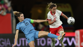 Adriana Achcińska w meczu z Holandią (fot. Getty). Obrazek przedstawia dynamiczne ujęcie z meczu piłki nożnej kobiet między Polską a Holandią, prawdopodobnie towarzyskiego spotkania w Gdańsku, gdzie Polki zremisowały z Holenderkami. Po prawej stronie, w białej koszulce z czerwonymi akcentami i orłem, znajduje się polska zawodniczka w trakcie prowadzenia piłki i biegu. Po lewej stronie, holenderska zawodniczka w błękitnym stroju z numerem 20, upada na murawę, jednocześnie wykonując wślizg lub próbując zablokować podanie (fot. Getty).