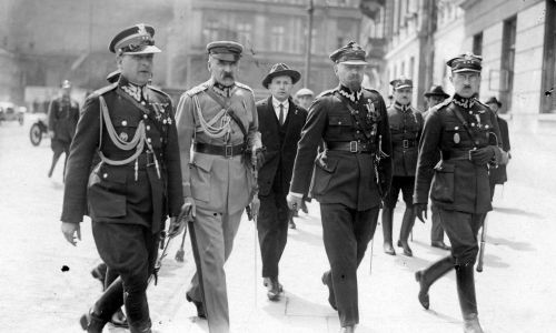 Rok 1926. Józef Piłsudski w towarzystwie pułkownika Bolesława Wieniawy-Długoszowskiego (pierwszy z lewej), majora Aleksandra Prystora (czwarty z lewej), pułkownika Wacława Stachiewicza (piąty z lewej) na ulicy Królewskiej w drodze do siedziby Sztabu Generalnego. Fot. NAC/IKC